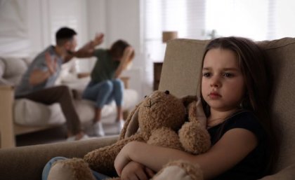 Child holding teddy bear while parents argue in background. Image, Adobe.